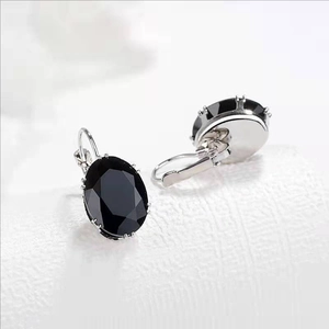 Macro shot of oval black gemstone earrings with polished silver lever-back closure