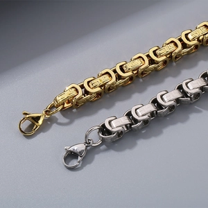 Macro detail of 8mm titanium steel Byzantine chain bracelets in gold and silver finish