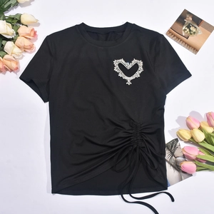 Détail d'un t-shirt noir avec cœur en strass et cordon de serrage latéral froncé