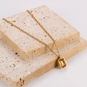 Champagne square sugar pendant necklace displayed on natural beige stone props