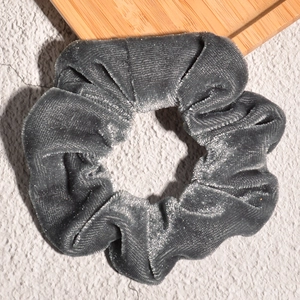 Macro shot of grey velvet scrunchie showing detailed texture and soft pleated fabric