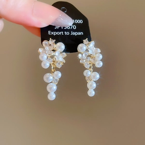 Macro shot of gold flower earrings with white pearls and sparkling crystal pendants