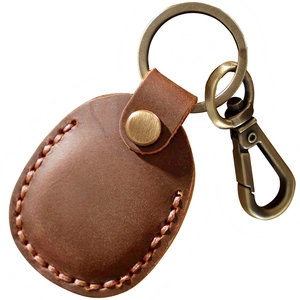 Brown leather Airtag case with metal keyring and spring hook on white background