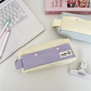 Detail of minimalist fabric pencil cases with zippers, heart buttons, and side handles