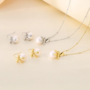 Macro shot of pearl necklace and earring set with metal bow details in gold and silver
