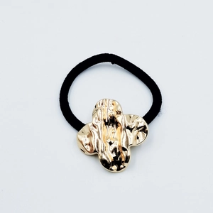 Detail of black elastic hair tie featuring a gold hammered wave texture alloy charm