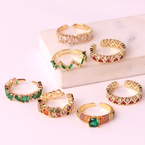 Macro detail of adjustable gold rings featuring colorful gemstones and emerald crystals