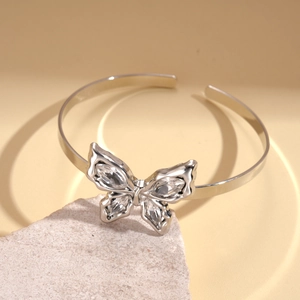Detail showing a silver butterfly arm cuff with sparkling rhinestones on a stone base
