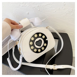 Close-up of vintage rotary telephone crossbody bag in cream patent leather with handset handle