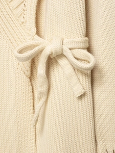 Macro detail of off-white rib-knit cardigan showing the soft fabric and bow tie decoration