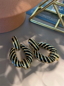 Macro shot of 18K gold plated twisted oval earrings with black zebra oil drip texture