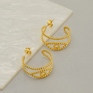 Close-up of gold beaded hoop earrings featuring a minimalist evil eye design detail