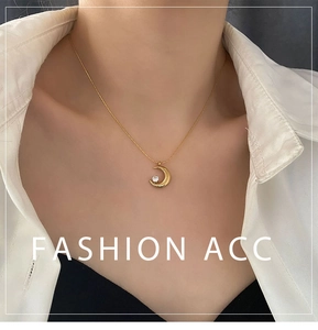 Detailed view of a gold crescent moon pendant necklace with a single zircon on a female model