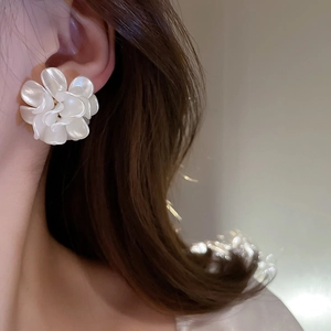 Detail showing elegant white acrylic flower earring worn on a model with soft lighting