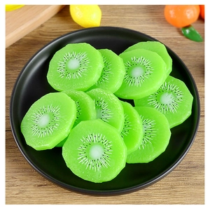 Vue détaillée de tranches de kiwi réalistes en PVC sur une assiette noire avec bois