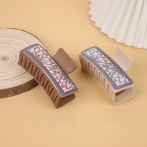 Detail showing two leather hair claws with pink sunflower patterns in brown and beige colors