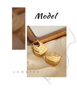 Detailed view of gold earrings with wave texture and high metallic gloss finish