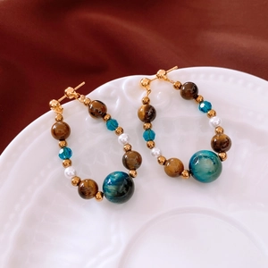 Détail de boucles d'oreilles perles avec œil de tigre et perles sur plat en céramique