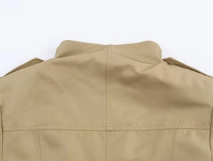 Detail der khakifarbenen Jacke mit Stehkragen, Schulterklappen und feinen Nähten am Stoff
