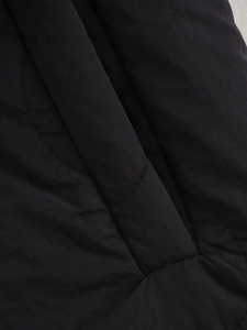 Detailed macro shot of black quilted fabric texture and stitching on casual jacket