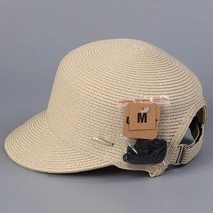 Dettaglio cappello in paglia con placca logo dorata laterale e fibbia regolabile