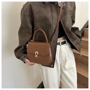 Detailed close-up of a brown PU leather vintage crossbody bag with gold metal buckle