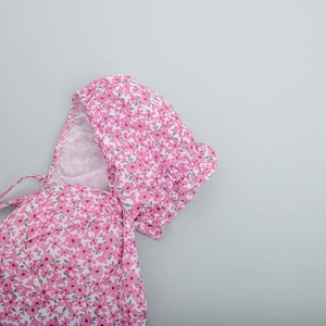 Close-up of pink floral dress featuring puff sleeves and pleated cuff details