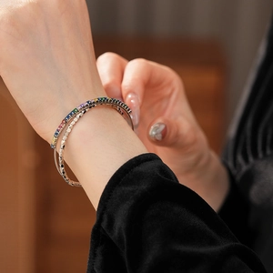Detailed view of silver bracelets with colorful zircons and faceted metal on wrist