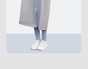 Détail de l'ourlet de l'imperméable long gris en EVA avec jean et baskets blanches