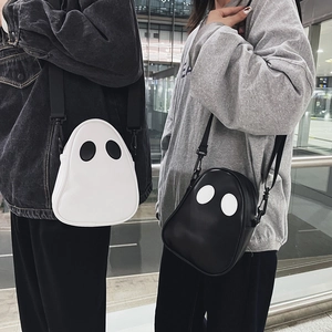 Detail of cute ghost-shaped PU leather crossbody bags in black and white worn by models