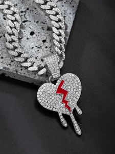 Macro shot of iced-out Cuban link chain and rhinestone dripping broken heart pendant