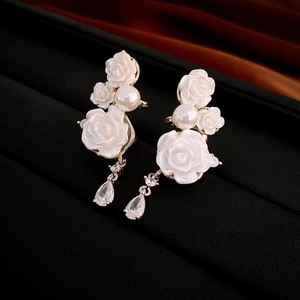 Detailed macro view of white rose petals, pearls and pear-shaped zircon on drop earrings