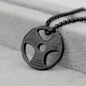 Macro shot of black dumbbell pendant necklace with inspirational fitness engraving details