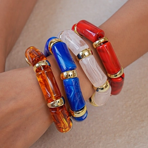 Detailed view of layered acrylic oval stretch bracelets in amber, blue, and marble finish