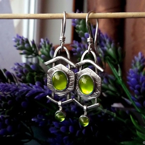 Pendientes vintage de plata con piedras verde oliva sobre un soporte de madera