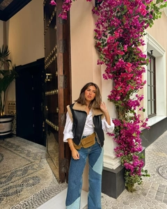 Gilet da donna in ecopelle nera con camicia bianca e jeans bicolore in stile marocchino