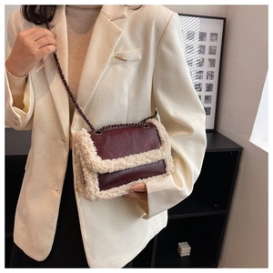 Detail of burgundy leather shoulder bag with white faux fur trim and chain strap