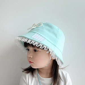 Detail of mint green cotton sun hat featuring delicate white lace and a pearl bow decoration