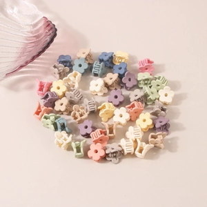 Matte flower petal hair clips in various macaron colors on a light pink background