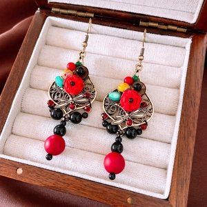 Close-up of vintage drop earrings with red beads and dragonfly relief on fabric