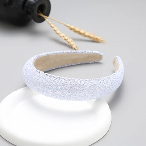 Detail of a wide white headband with a glittery texture on a white round base