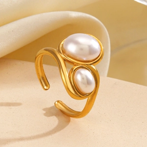 Elegant gold S-shaped adjustable ring with two white pearls on silk fabric background