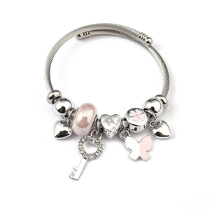 Detail view of silver charm bracelet with pink butterfly, heart key, and glass beads