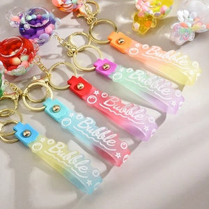Detail of colorful liquid oil keychains with bubble charms and gradient silicone wristlets