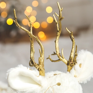 Christmas white plush reindeer ornament with gold antlers on festive warm bokeh background