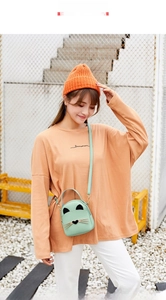 Detail of mint green cat-shaped crossbody bag with metal whiskers and adjustable strap