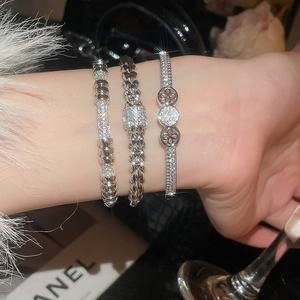 Close-up of three silver-plated zircon bracelets with clover and woven texture on wrist