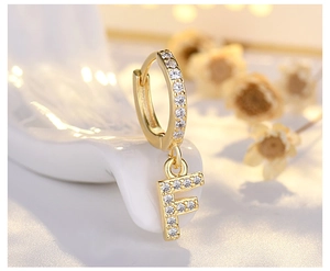 Macro view of gold S925 silver hoop earring with letter F pendant and white zircon stones