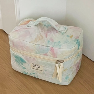 Close-up of watercolor quilted toiletry bag featuring a top handle and zip closure