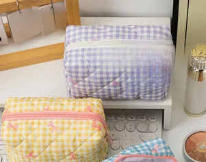 Close-up of quilted checkered cosmetic bag with bow embroidery and zipper closure